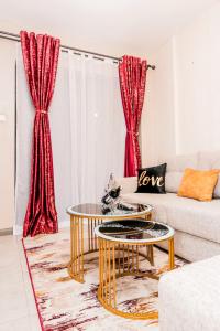 uma sala de estar com mesas douradas e cortinas vermelhas em StayEasy Tsavo em Nairobi