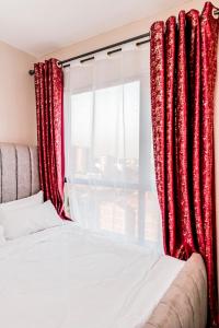 um quarto com cortinas vermelhas, uma cama e uma janela em StayEasy Tsavo em Nairobi