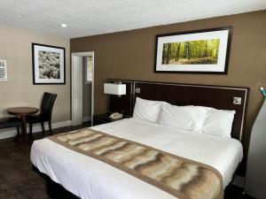 a hotel room with a large bed and a table at Champlain Motor Inn in Pembroke