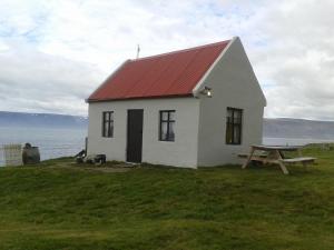 a white house with a red roof and a picnic table at Hænuvík Cottages in Hnjótur