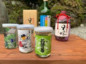 Iya Kankou Ryokan في ميوشي: طاولة مع أربعة بيارات من الطعام وزجاجة من النبيذ