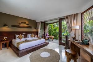 a bedroom with a large white bed and a desk at Honai Resort in Ubud