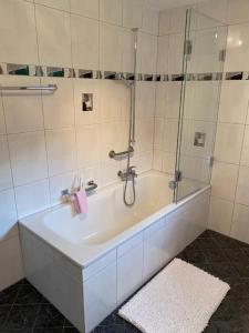 uma casa de banho com uma banheira e um chuveiro em vidro. em Ferienwohnung "Spel Rein" Cumpadials inmitten der Surselva em Compadials