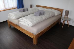 uma cama de madeira com lençóis brancos e almofadas em Ferienwohnung "Spel Rein" Cumpadials inmitten der Surselva em Compadials