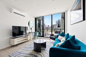 a living room with a blue couch and a tv at The Marker Apartments Melbourne in Melbourne