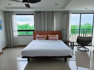 Schlafzimmer mit einem Bett, einem Stuhl und Fenstern in der Unterkunft Tamarind ณ บางคล้า ที่พักริมแม่น้ำ in Ban Khlong Tha Thong Lang