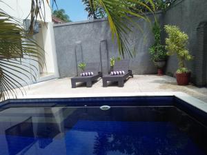 una piscina con 2 bancos junto a una casa en Bali Paradise Apartments, en Sanur