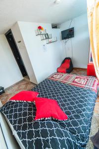 a bedroom with a bed with red pillows on it at HOSPEDAJE DON PABLO in Otavalo