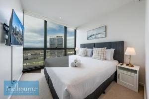 Melbourne Private Apartments - Collins Street Waterfront, Docklands في ملبورن: غرفة نوم بسرير كبير مع نافذة كبيرة