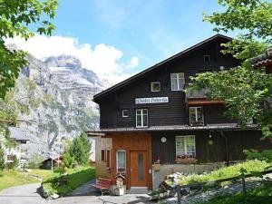 ein schwarzes Haus mit einem Berg im Hintergrund in der Unterkunft Helvetia Heinemann 4 Bett Wohnung in Mürren