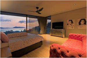a bedroom with a bed and a flat screen tv at The Cube Ocean View Pool Villa Kalim in Patong Beach