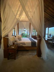 a bedroom with a canopy bed and a table at Sarini Villas in Blahbatu
