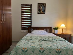 a bedroom with a bed and a table and a window at Solomon Apartments,Alappuzha beach. in Alleppey
