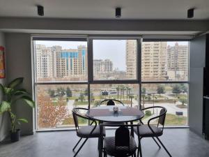 uma mesa e cadeiras num quarto com uma grande janela em Art Studio Park View 53 em Baku