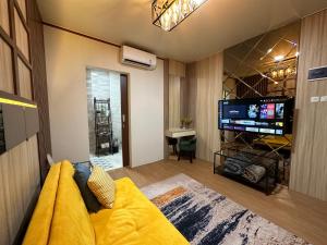 a living room with a yellow couch and a flat screen tv at Deluxe Residence Kalibata 8 in Jakarta