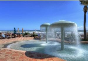 a fountain in a pool with a beach in the background at Beautiful one bedroom oceanfront condo in Daytona Beach