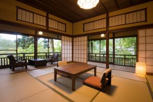 Cette chambre comprend une table, des chaises et des fenêtres. dans l'établissement Matsuzakaya Honten, à Hakone