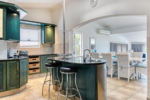 a kitchen with green cabinets and a counter with bar stools at Rontree Reflections in Cape Town