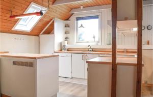 una cucina con armadi bianchi e soffitto in legno di Beautiful Home In Ringkøbing With Sauna a Klegod