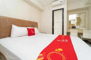 um quarto com uma cama branca e um cobertor vermelho em RedLiving Apartemen 19 Avenue - Amanah Room em Tangerang