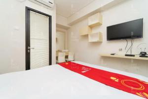 um quarto com uma cama branca com um cobertor vermelho em RedLiving Apartemen 19 Avenue - Amanah Room em Tangerang