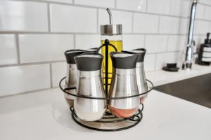 a group of condiments in a metal container on a kitchen counter at Casa Azure - New Modern 3 BR, Med Center, NRG, UH in Houston