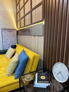 a room with a yellow couch and a table with a clock at Deluxe Residence Kalibata 8 in Jakarta
