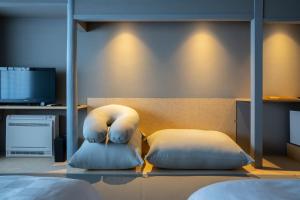 a room with two pillows on a bed with a tv at Kameya Hotel in Tsuruoka