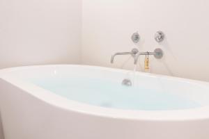 a white bath tub with a faucet in a bathroom at Kameya Hotel in Tsuruoka