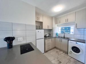 a kitchen with white cabinets and a washer and dryer at Escape to 85 Cascades in Umdloti Beach in Umdloti