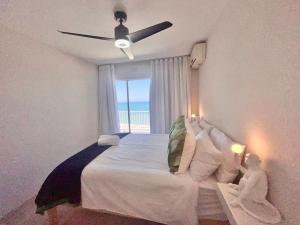 a bedroom with a bed with a ceiling fan and a window at Escape to 85 Cascades in Umdloti Beach in Umdloti