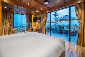 a bedroom with a large bed and a large window at Bonny Boutique Hotel Da Nang in Danang