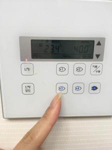 una mano preme un pulsante su una macchina di New world hwani House a Seul