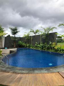 a large blue swimming pool with a wooden deck at Sawah Tamanan Villa & Resort in Yogyakarta