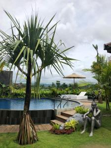 a statue of a man sitting under a palm tree next to a pool at Sawah Tamanan Villa & Resort in Yogyakarta