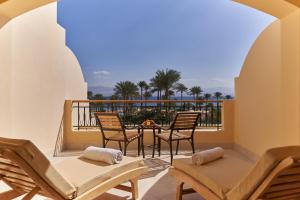 uma varanda com mesa, cadeiras e palmeiras em Mosaique Beach Resort Taba Heights em Taba