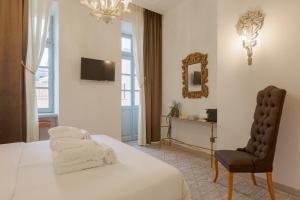 a bedroom with a bed and a chair and a mirror at Residenza di Fedralia in Nafplio