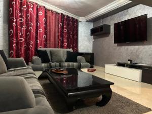 uma sala de estar com um sofá e uma televisão em Duplex haut standing à 5min de la plage2 em Agadir