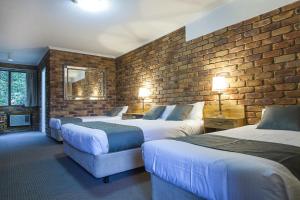 een hotelkamer met 2 bedden en een bakstenen muur bij Montville Mountain Inn in Montville