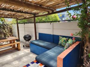 a blue couch sitting under a pergola on a patio at Spacious cottage near Bloubergstrand beach in Cape Town +8 photos