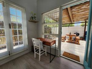 a room with a table and a chair and windows at Spacious cottage near Bloubergstrand beach in Cape Town