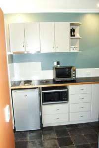 a kitchen with white cabinets and a microwave at Highland Cabins and Cottages at Bronte Park in Bronte