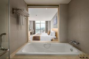 a bath tub in a bathroom with a bedroom at The Reed Hotel in Ninh Binh