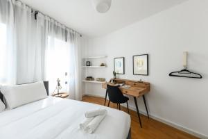 a white bedroom with a desk and a bed at Chic 3BR Apt w Balcony & Parking by Tel Aviv Port by Sea N' Rent in Tel Aviv