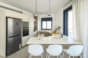 una cocina con encimera blanca y sillas. en Chic 3BR Apt w Balcony & Parking by Tel Aviv Port by Sea N' Rent en Tel Aviv