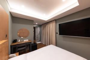 Habitación de hotel con cama, escritorio y TV. en ARA Hotel, en Seúl