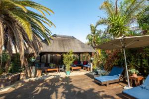 a gazebo with chairs and an umbrella and palm trees at Gecko Ridge in Swakopmund