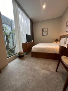 Sawah Tamanan Villa & Resort في يوغياكارتا: غرفة نوم بسرير وتلفزيون ونوافذ