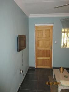 a room with a door and a television on a wall at LISANÉ ACCOMMODATION in Middelburg