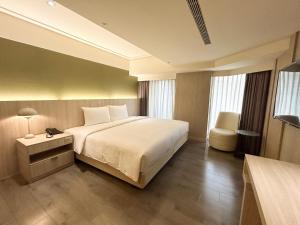 a bedroom with a large white bed and a chair at Green Hotel - Tea Way in Taichung